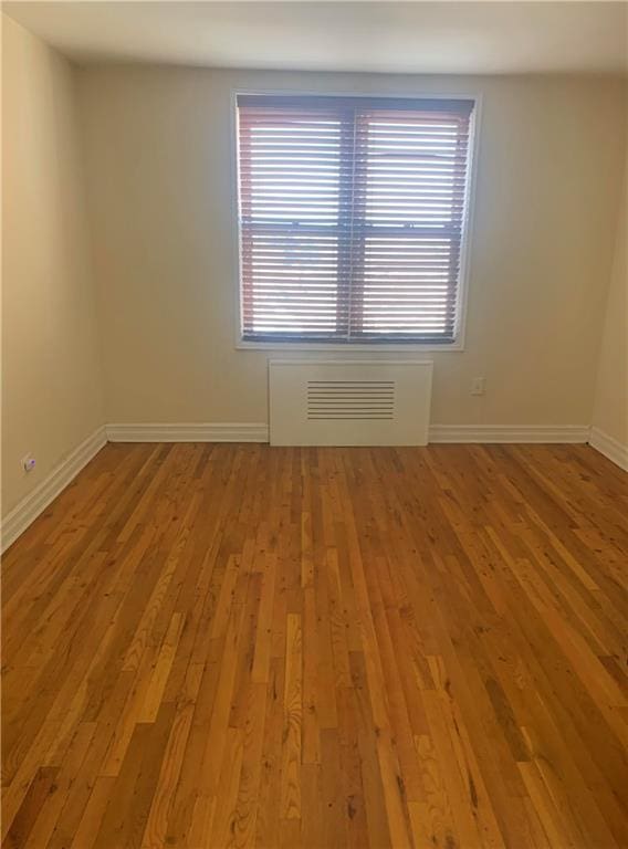 spare room featuring baseboards, wood-type flooring, and visible vents