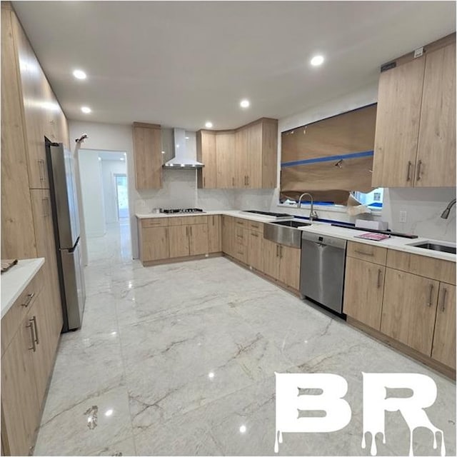 kitchen with a sink, light countertops, appliances with stainless steel finishes, wall chimney range hood, and marble finish floor