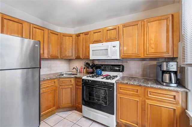 kitchen with white appliances, a sink, light stone countertops, backsplash, and light tile patterned flooring