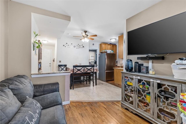 living area with a ceiling fan and light wood-type flooring