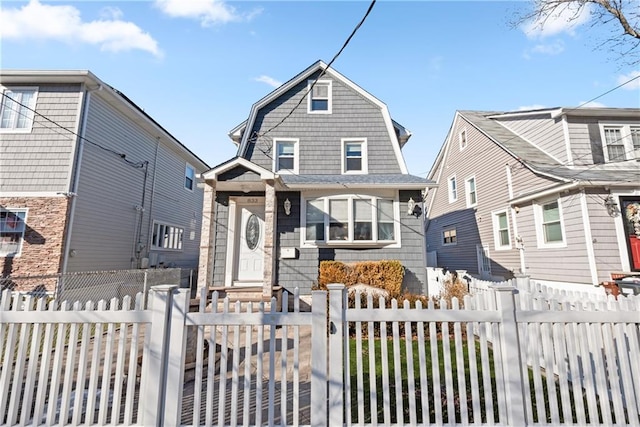 view of front of home with a fenced front yard and a gambrel roof