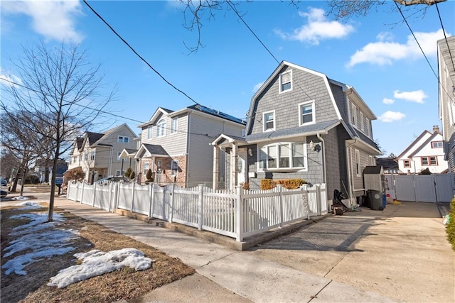 view of front facade with a fenced front yard, a residential view, a gate, and a gambrel roof