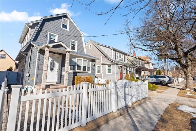 view of front of home featuring a fenced front yard, a residential view, and a gambrel roof