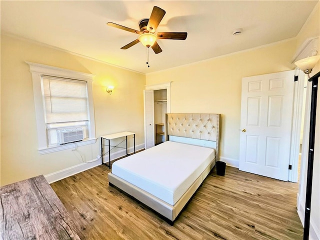 bedroom with cooling unit, a closet, baseboards, and wood finished floors