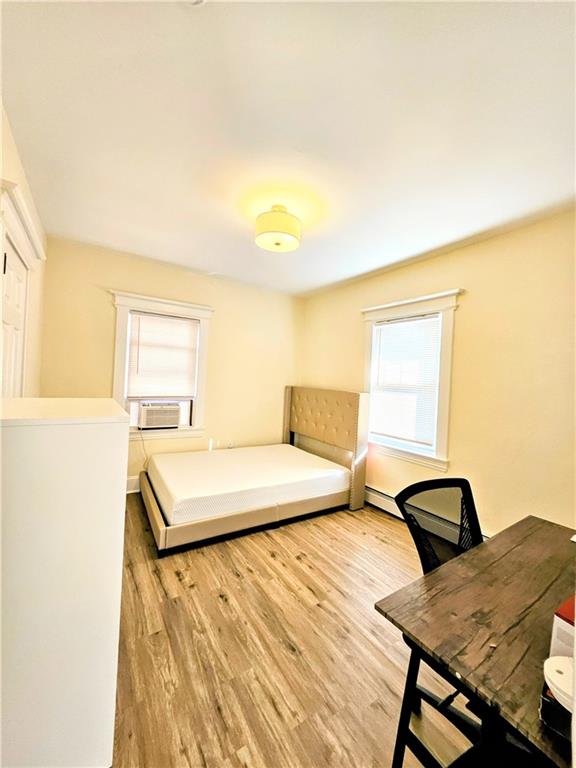 bedroom with cooling unit and wood finished floors