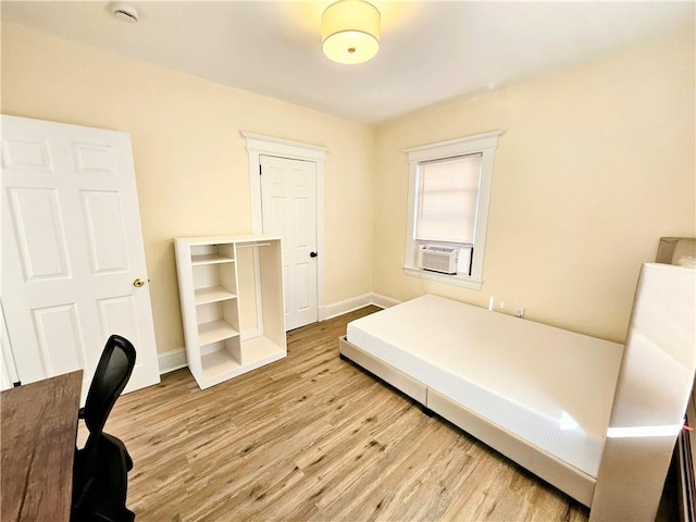 bedroom featuring cooling unit, wood finished floors, and baseboards