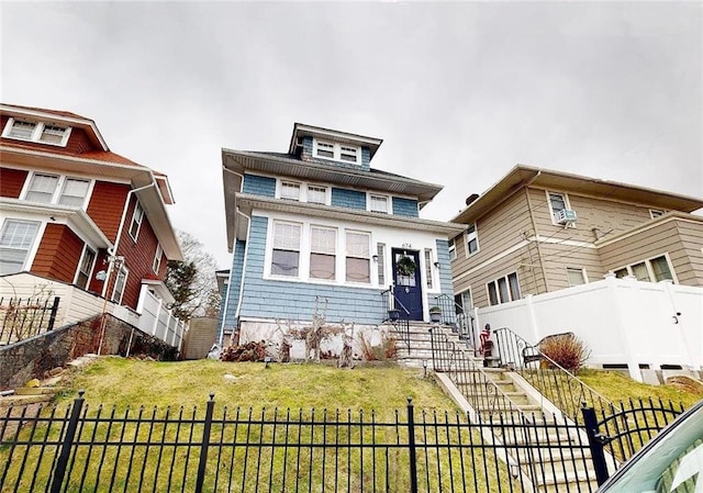 american foursquare style home featuring entry steps, a front lawn, and fence