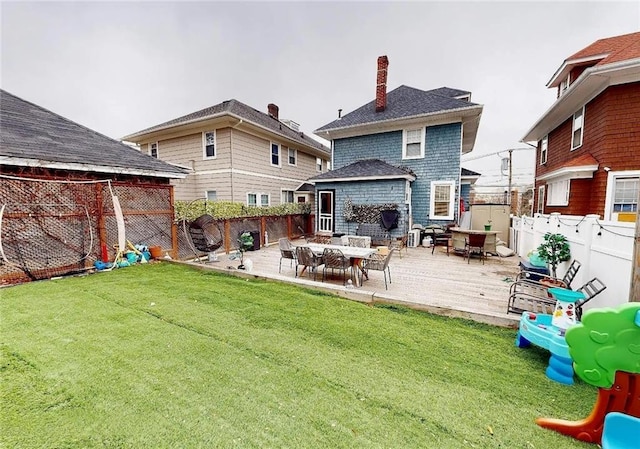 back of property featuring a fenced backyard, a chimney, a deck, and a yard