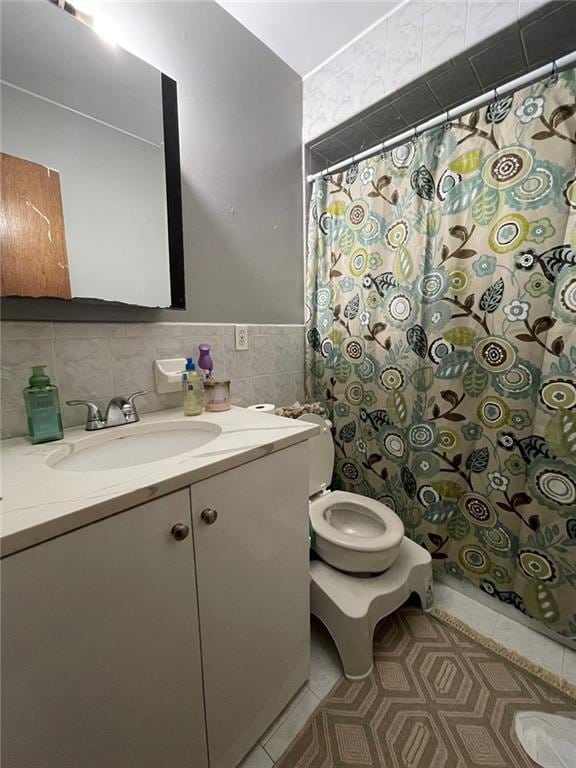 bathroom featuring a shower with shower curtain, toilet, tile patterned floors, vanity, and tile walls