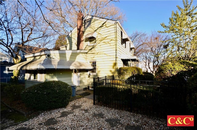 view of side of home featuring a chimney and fence