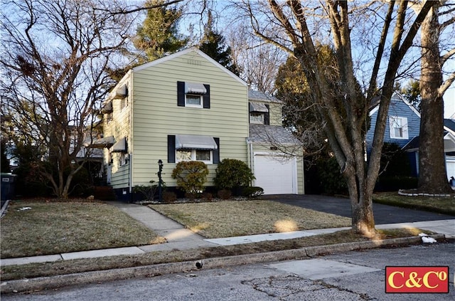 traditional-style home with aphalt driveway, a front yard, and an attached garage