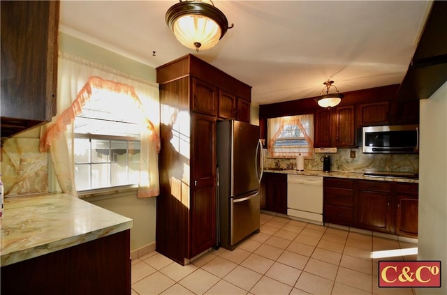 kitchen featuring light tile patterned floors, stainless steel appliances, baseboards, light countertops, and backsplash