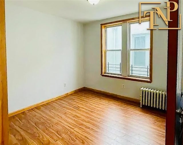 spare room featuring radiator heating unit, wood finished floors, and baseboards