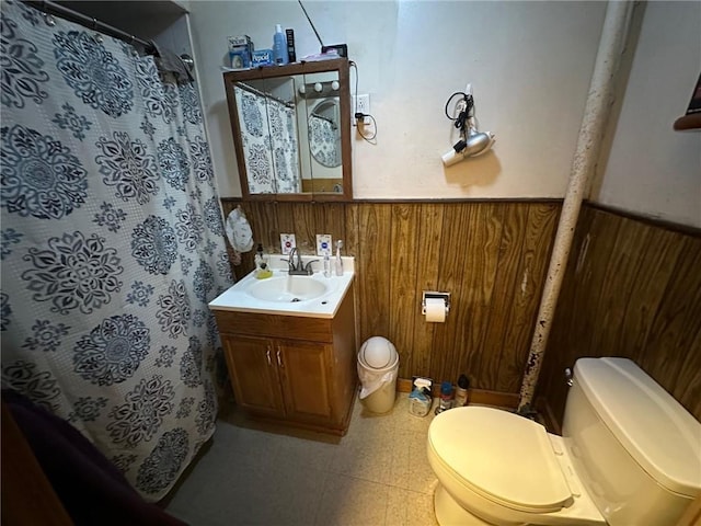 full bath with toilet, wainscoting, wood walls, and tile patterned floors