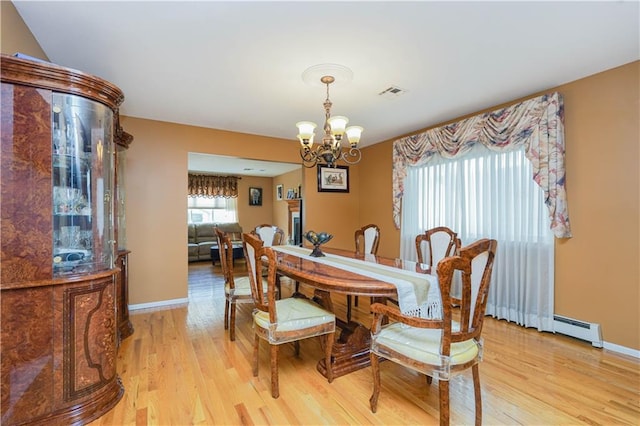 dining space with a chandelier, light wood finished floors, visible vents, and baseboards