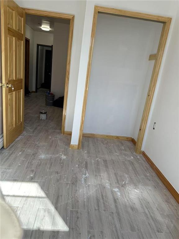 corridor featuring light wood finished floors and baseboards