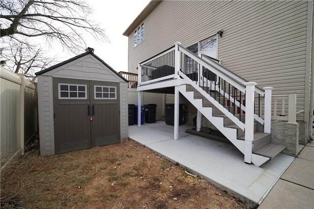 exterior space with stairway, an outbuilding, a storage unit, fence, and a patio area