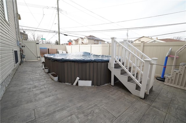 view of patio / terrace featuring a wooden deck, a gate, a fenced backyard, and a jacuzzi