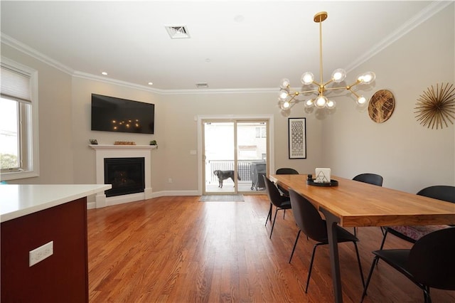 dining space featuring a fireplace, crown molding, light wood-style flooring, and baseboards