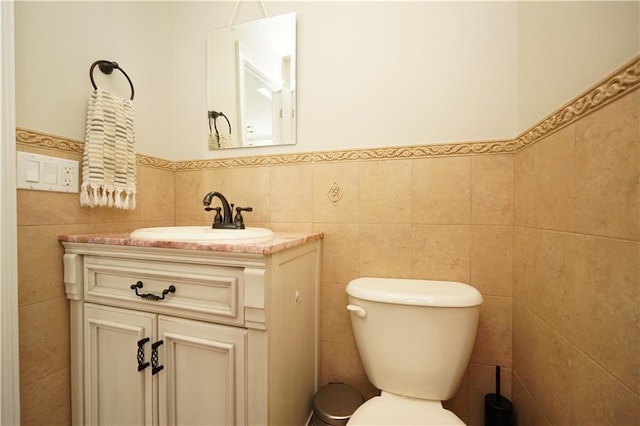 half bathroom featuring tile walls, vanity, and toilet