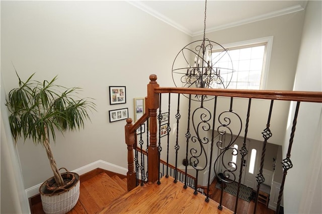 stairs with a chandelier, crown molding, baseboards, and wood finished floors