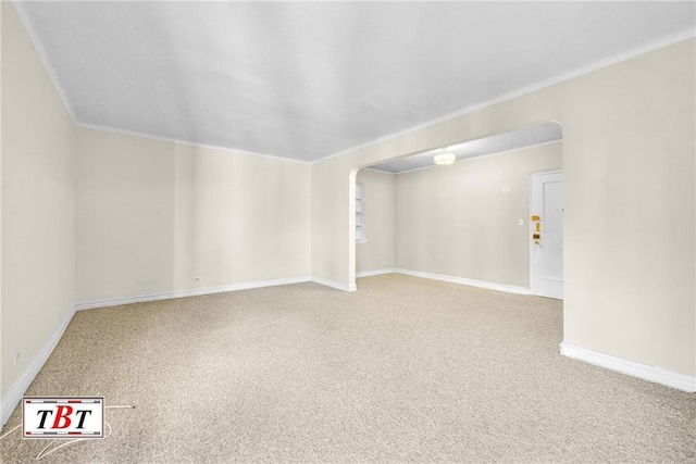 carpeted spare room with arched walkways, crown molding, and baseboards