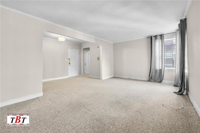 unfurnished room with carpet floors, baseboards, and arched walkways