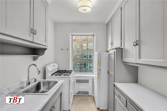 kitchen with a sink, light countertops, light tile patterned flooring, radiator heating unit, and white appliances
