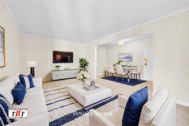 carpeted living area with baseboards and arched walkways