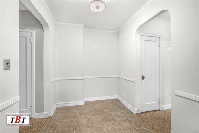 corridor with arched walkways, baseboards, and crown molding