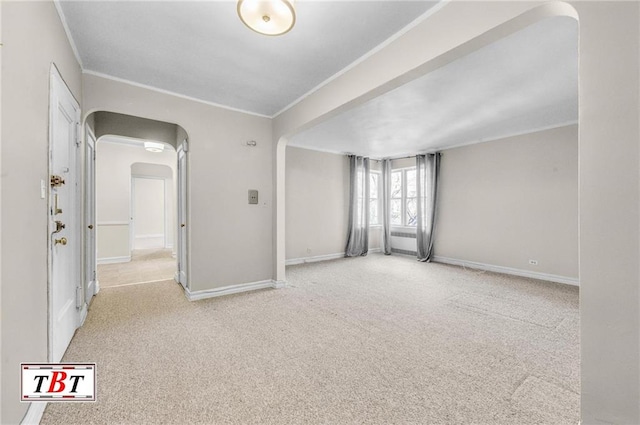 carpeted empty room with arched walkways, crown molding, and baseboards