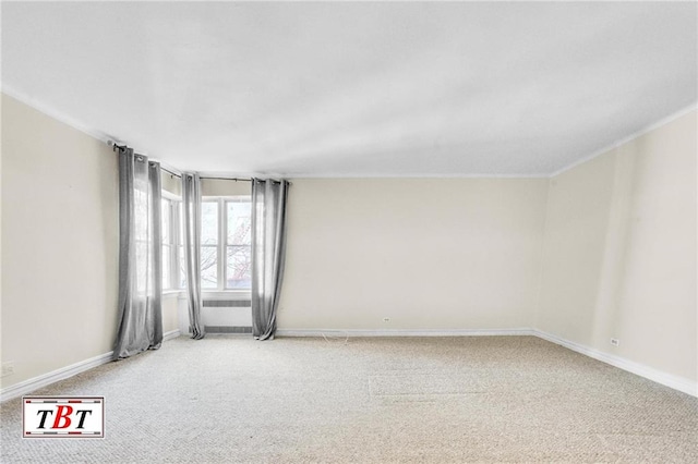carpeted spare room featuring crown molding and baseboards