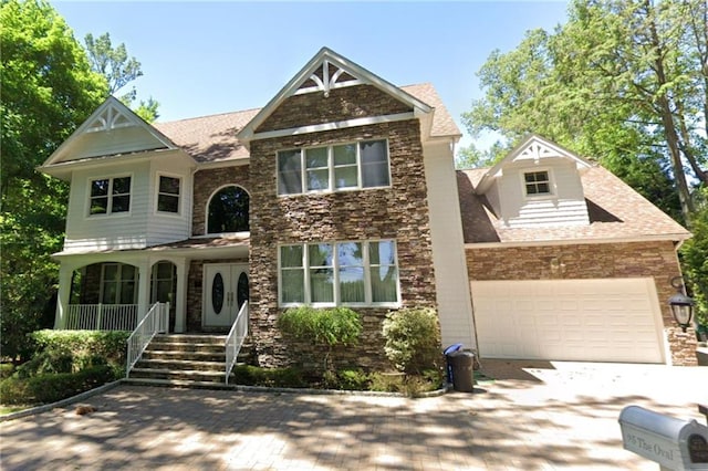 view of front of property featuring stone siding, concrete driveway, a porch, and a garage