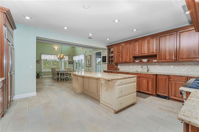 kitchen featuring a center island, open shelves, a sink, backsplash, and light stone countertops