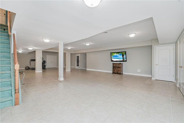 finished below grade area with baseboards, stairs, and light tile patterned flooring