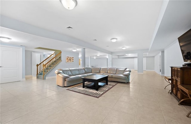 living room featuring light tile patterned floors, visible vents, stairway, and baseboards