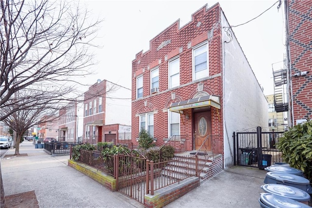 view of front facade featuring brick siding, fence, and stucco siding