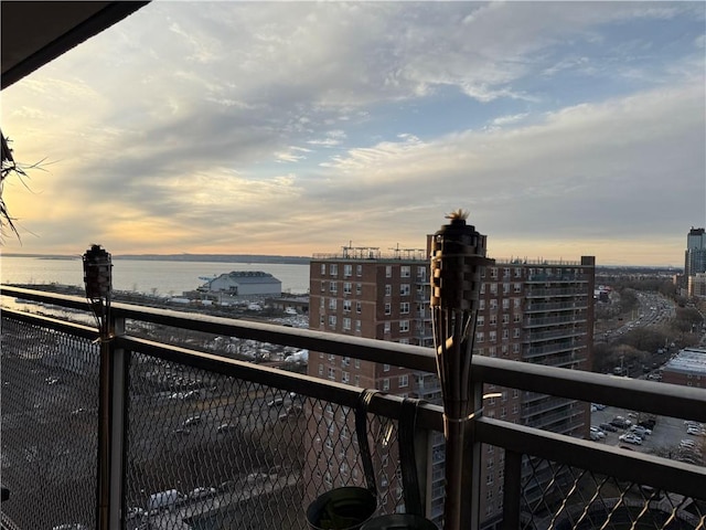 balcony at dusk with a water view and a city view