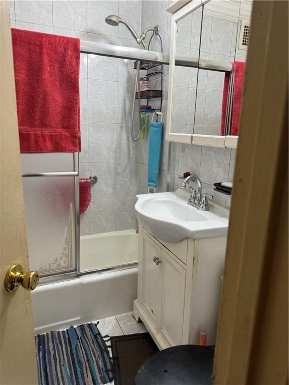 full bathroom with tasteful backsplash, tile walls, combined bath / shower with glass door, and vanity