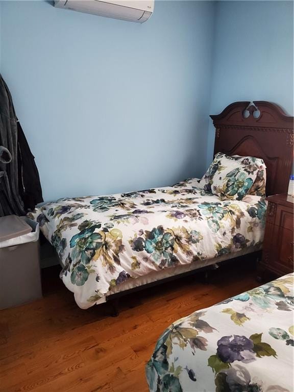 bedroom with an AC wall unit and wood finished floors