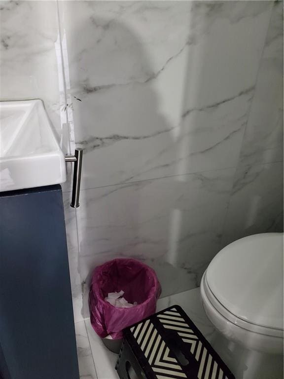 bathroom with marble finish floor, a marble finish shower, vanity, and toilet