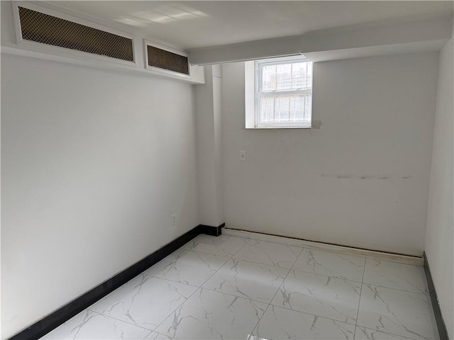 basement featuring marble finish floor and baseboards