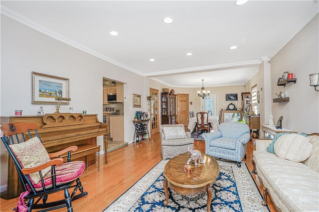 living room featuring a chandelier, recessed lighting, ornamental molding, and light wood-style flooring