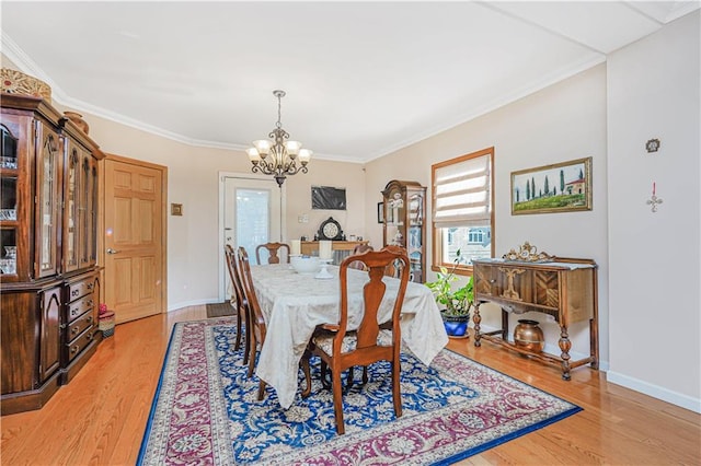 dining space with light wood-type flooring, a notable chandelier, baseboards, and crown molding