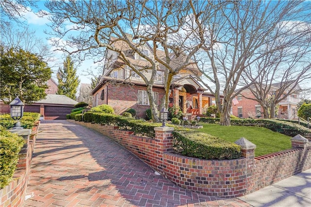 view of front of home with a garage, brick siding, a front lawn, and an outbuilding