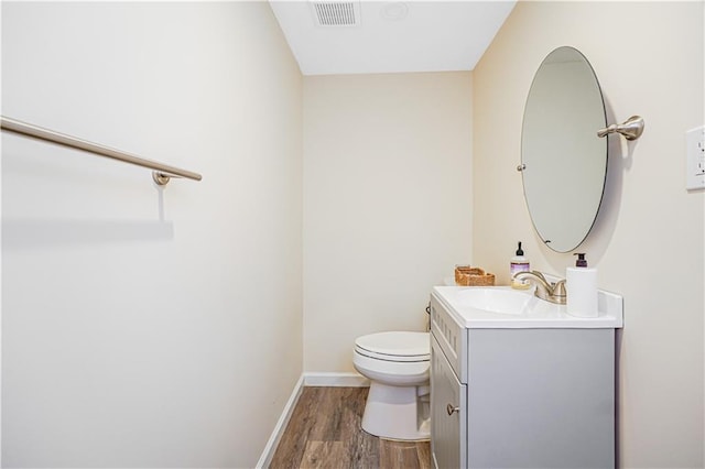 bathroom with toilet, wood finished floors, visible vents, vanity, and baseboards