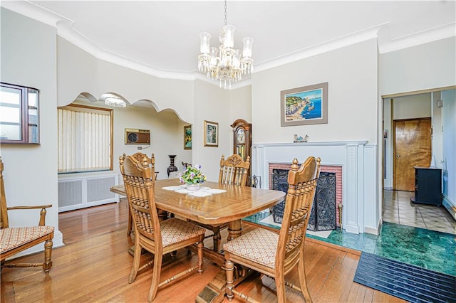 dining space with a fireplace with flush hearth, light wood-type flooring, and ornamental molding