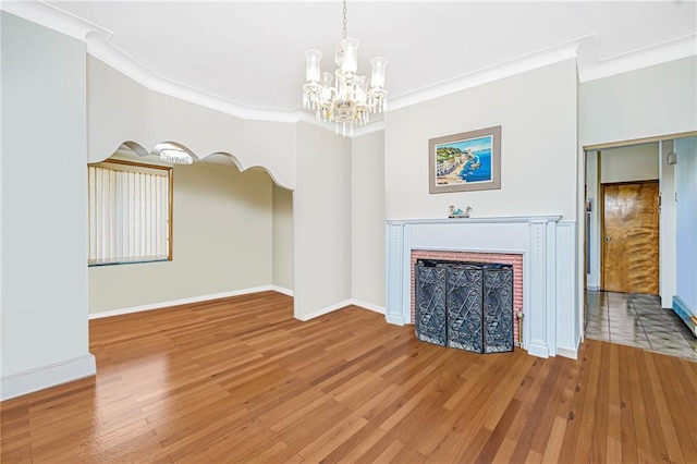 unfurnished living room with crown molding, a fireplace, baseboards, and wood finished floors