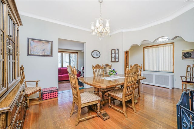 1265 86th St, Brooklyn, NY 11228 - dining area featuring radiator, a chandelier, light wood-style flooring, crown molding, and arched walkways