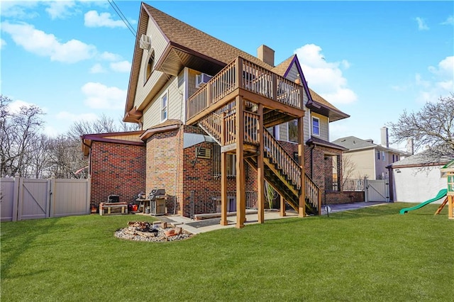 back of house with a gate, stairway, a lawn, and brick siding